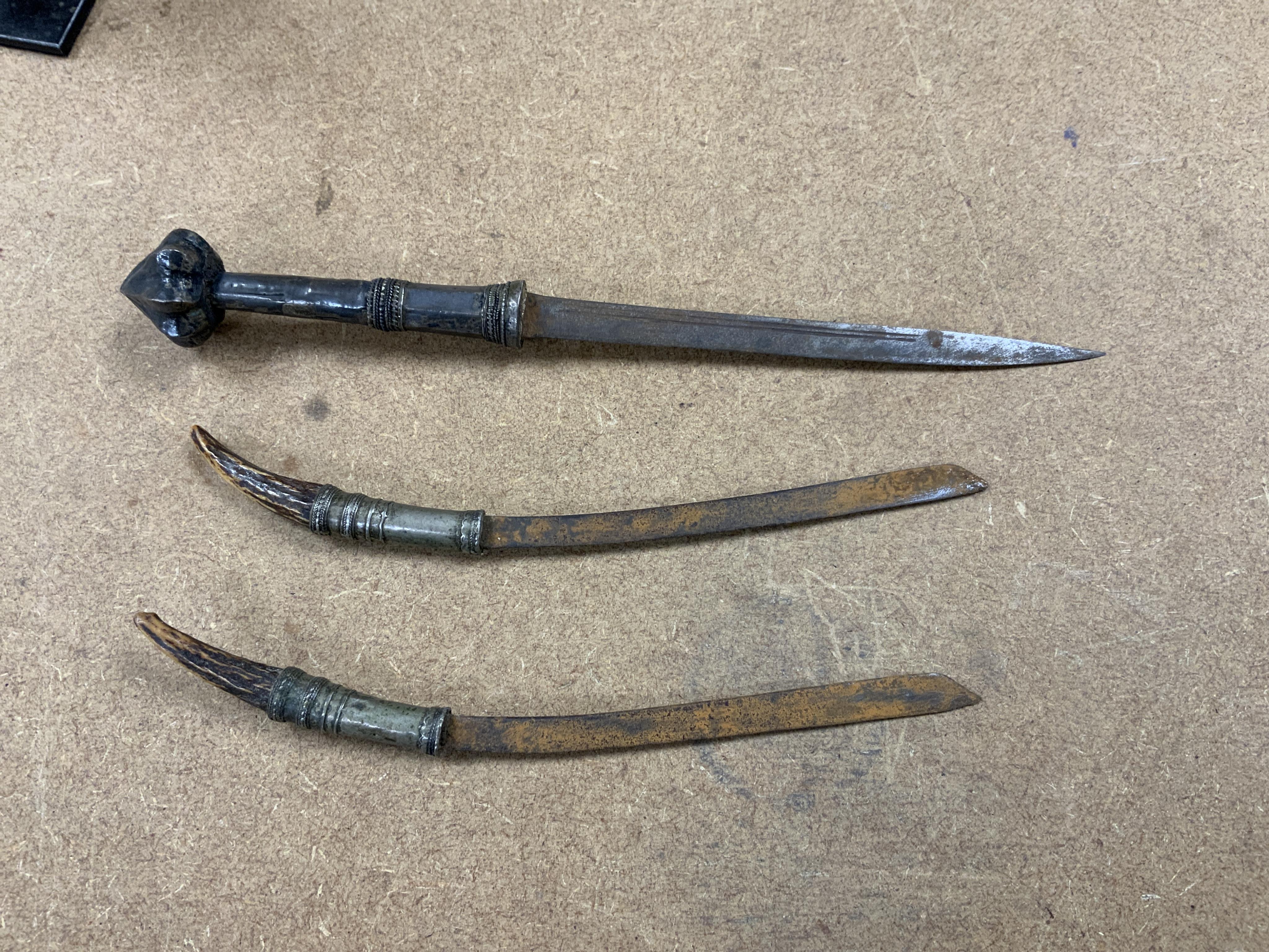 A Burmese dagger dha, blade 14.5cm, hilt and sheath covered in sheet silver filigree decoration, together with an unusual pair of small Burmese knives with silver mounted stag horn handles and silver covered sheath, both